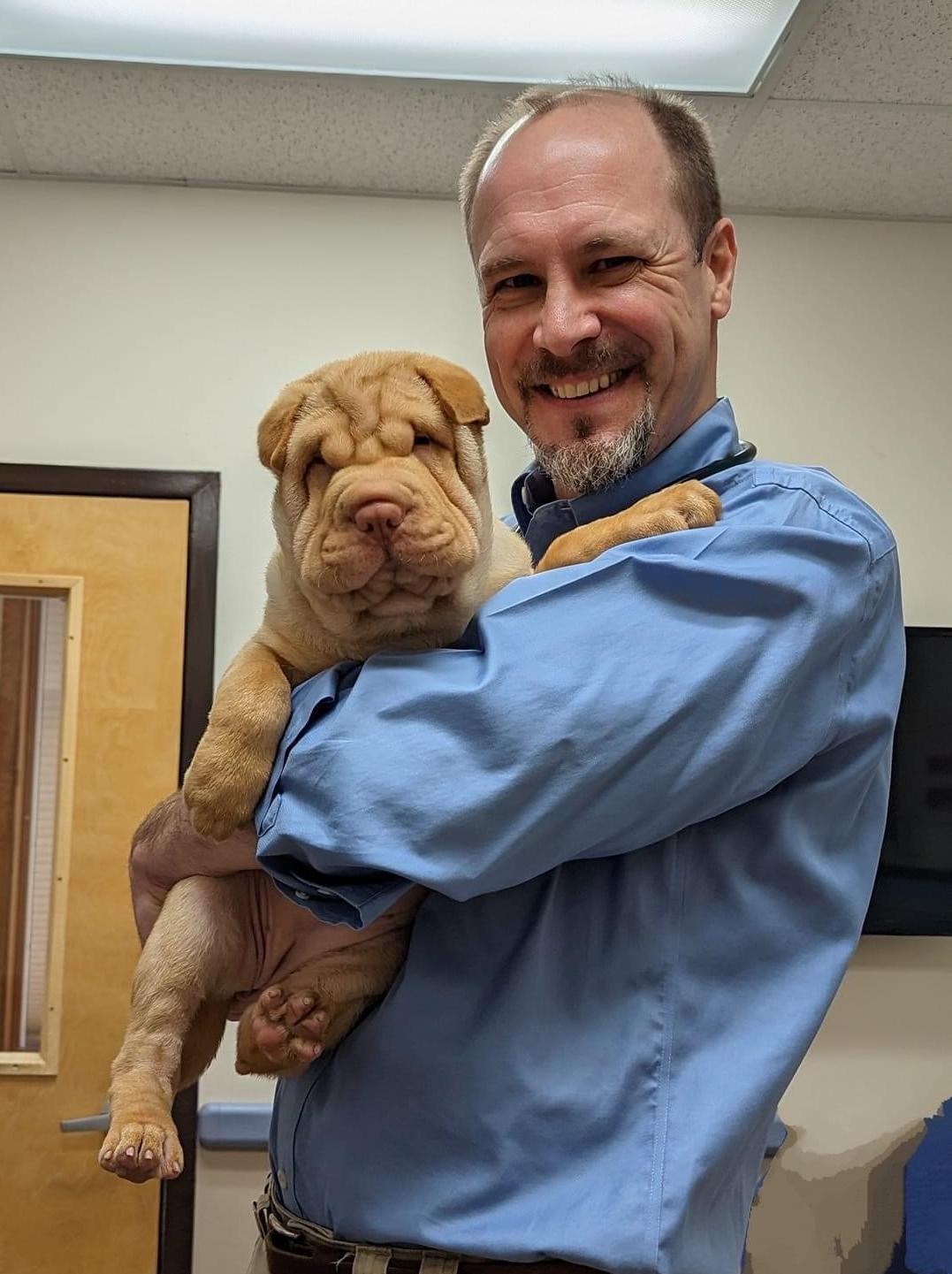 Dr. Novak holding a tan dog
