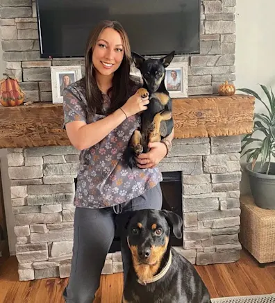 Staff photo of Taylor holding a small black dog and a bigger black dog sitting in front of her. Staff photo of Taylor holding a small black dog and a bigger black dog sitting in front of her.
