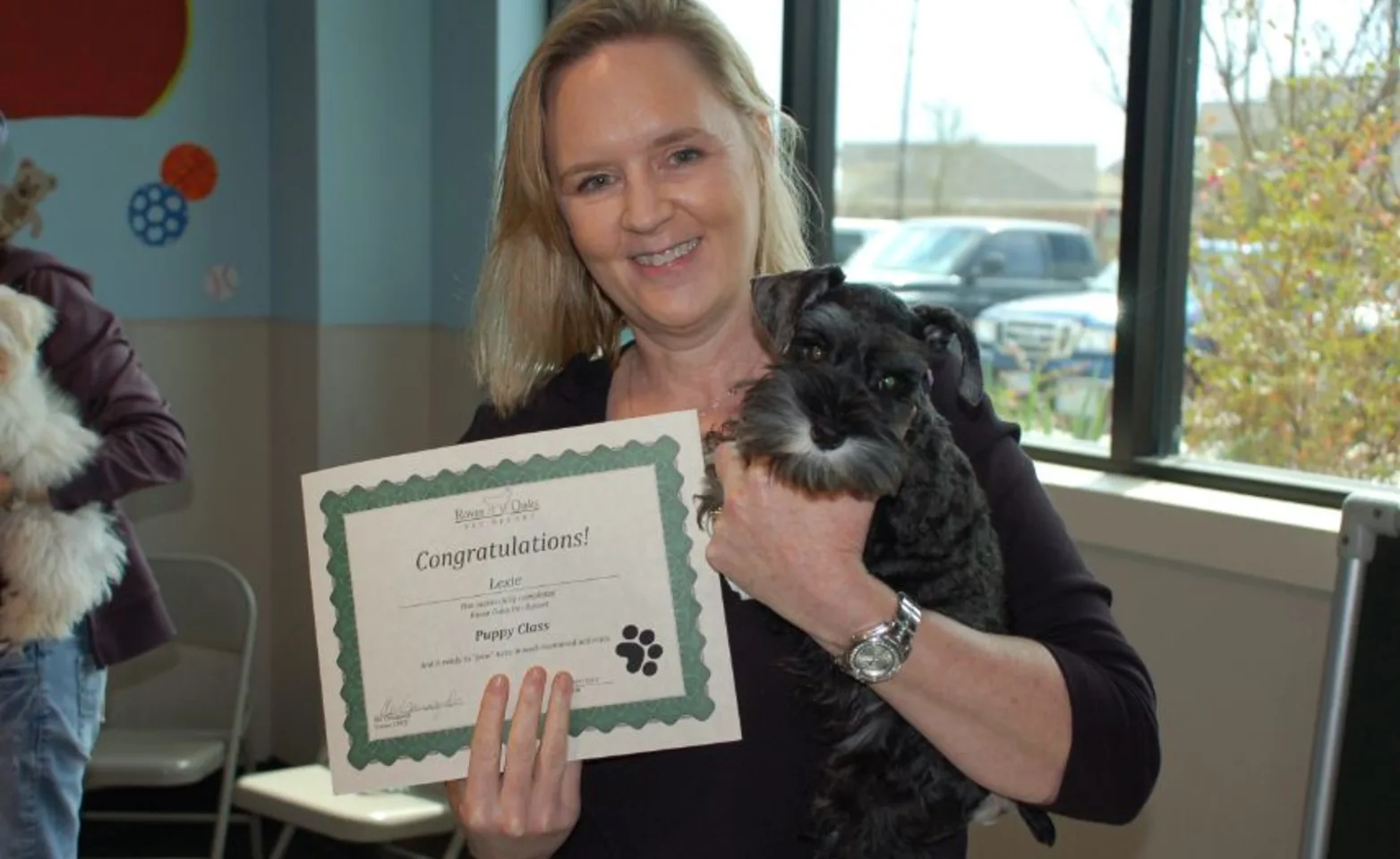 A Woman Holding a Small Dog and a Certificate