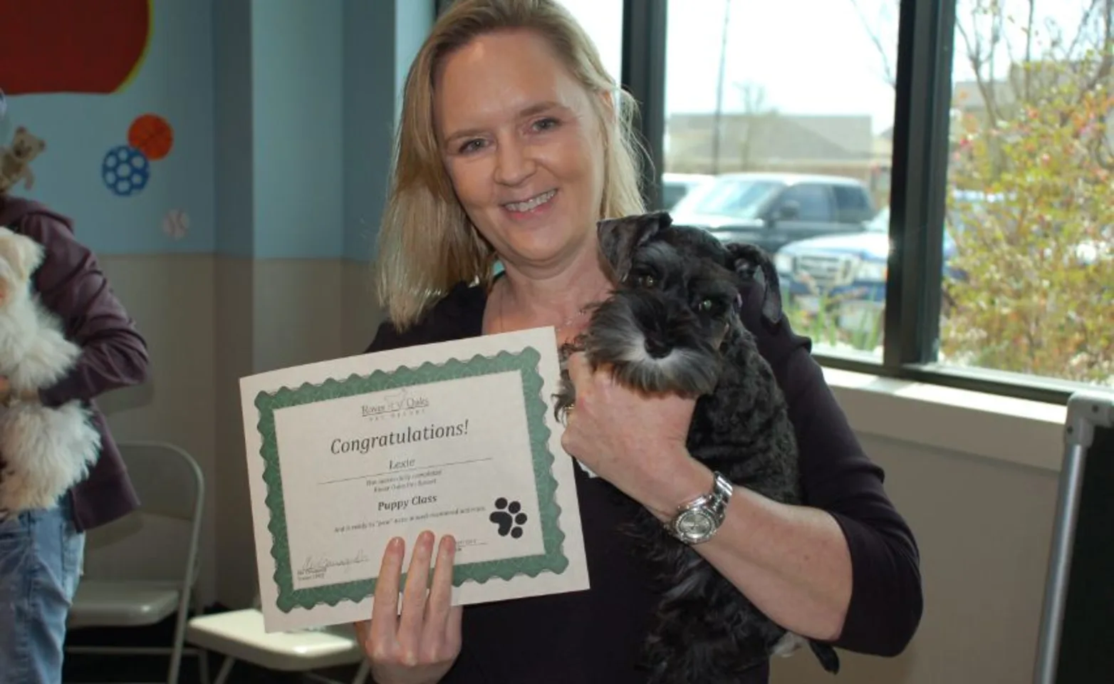 A Woman Holding a Small Dog and a Certificate A Woman Holding a Small Dog and a Certificate