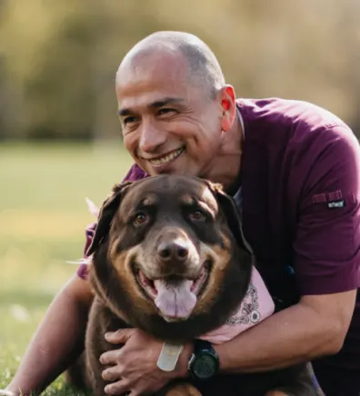 Ramon Lopez laying in grass with a large brown dog 