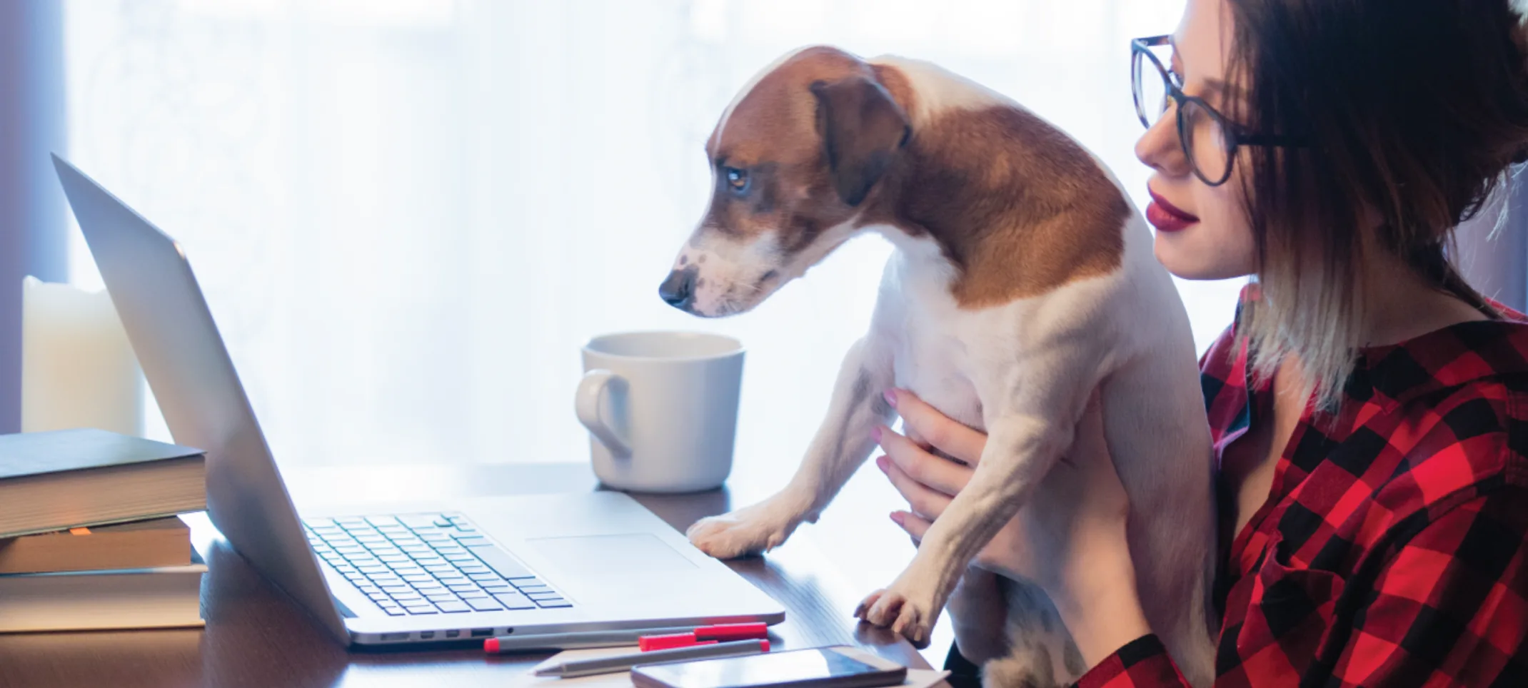 Woman holding dog up to laptop