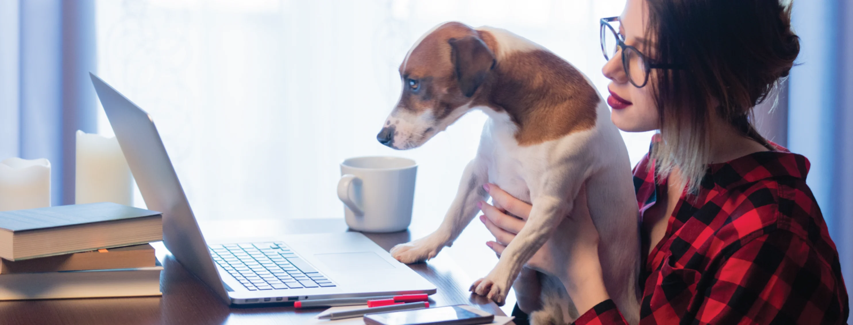 Woman holding dog up to laptop