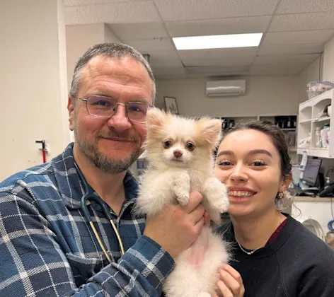A small puppy being held by two people A small puppy being held by two people