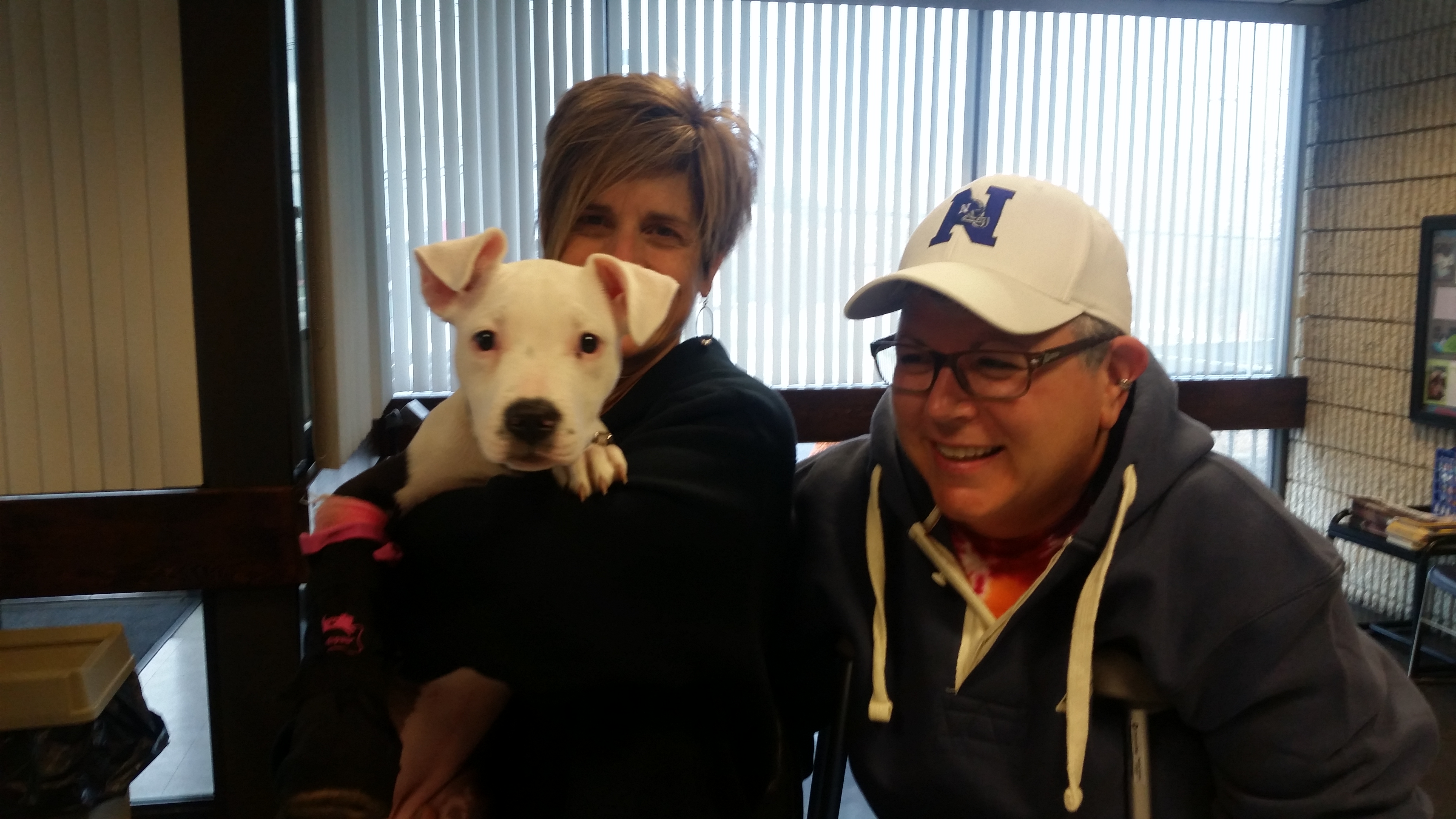 White puppy with both of its owners.