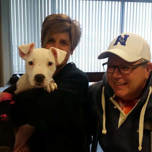 White puppy with both of its owners. White puppy with both of its owners.