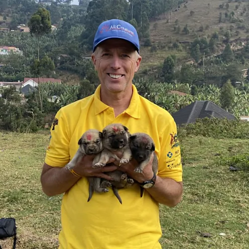 Dr. Joe smiling standing outside holding 3 small puppies Dr. Joe smiling standing outside holding 3 small puppies