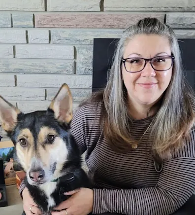 Tanya smiling and hugging two dogs