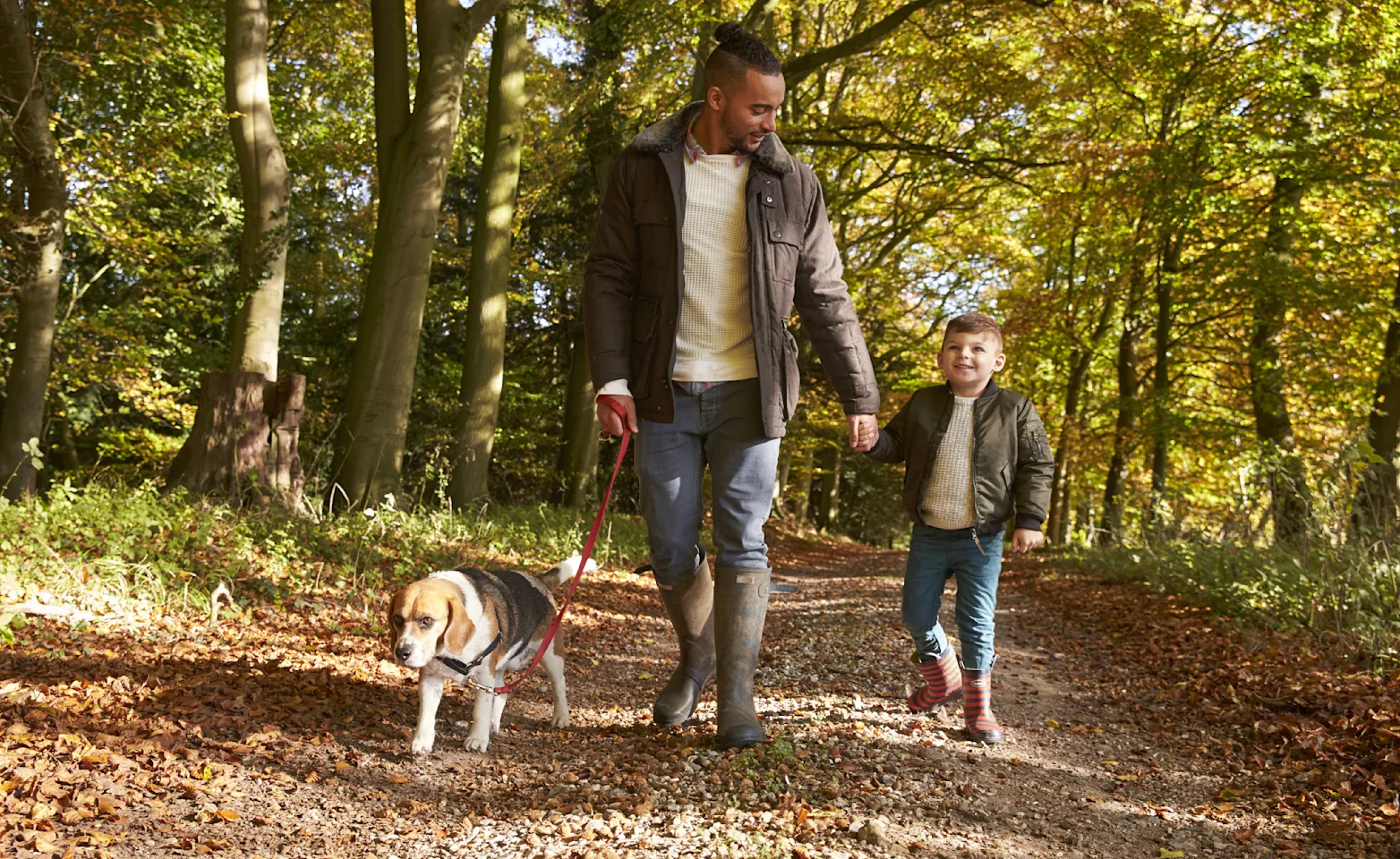 Man and kid taking dog on walk through woods