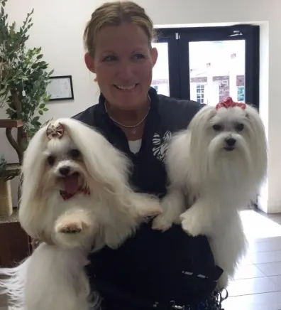 Lori holding two white dogs with bows