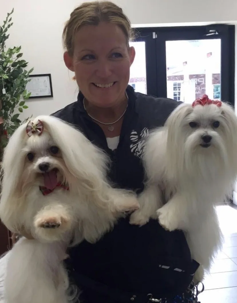 Lori holding two white dogs with bows