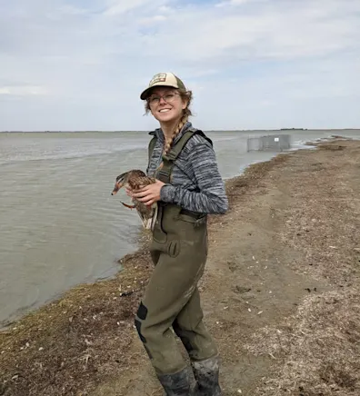 Brenna near a lake while holding a duck. Brenna near a lake while holding a duck.