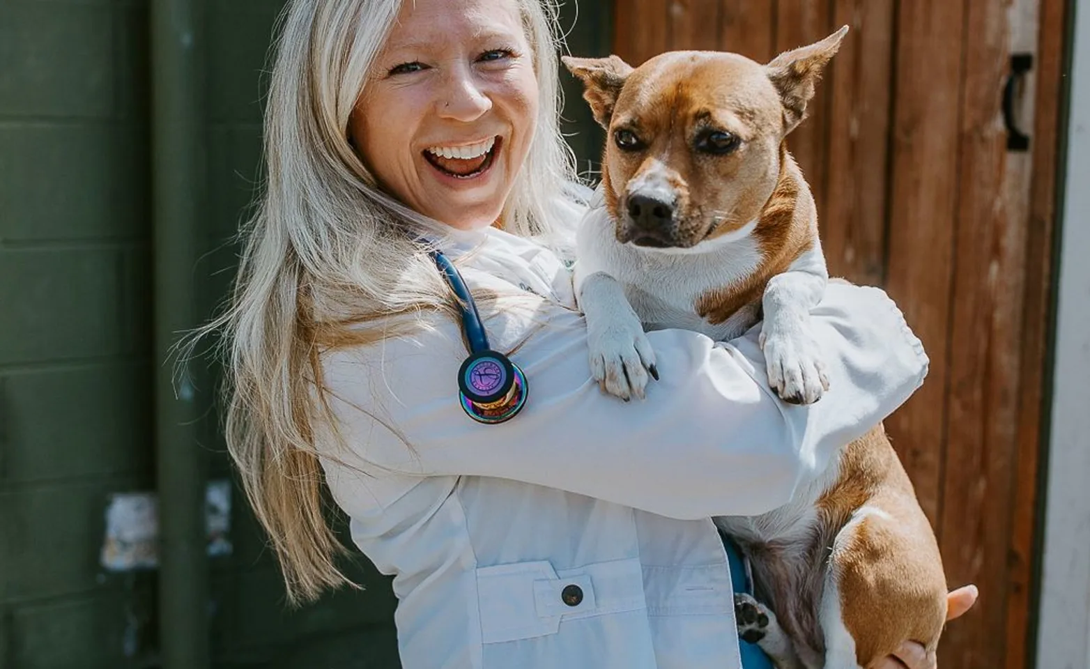 Woman in doctor coat holding brown dog Woman in doctor coat holding brown dog