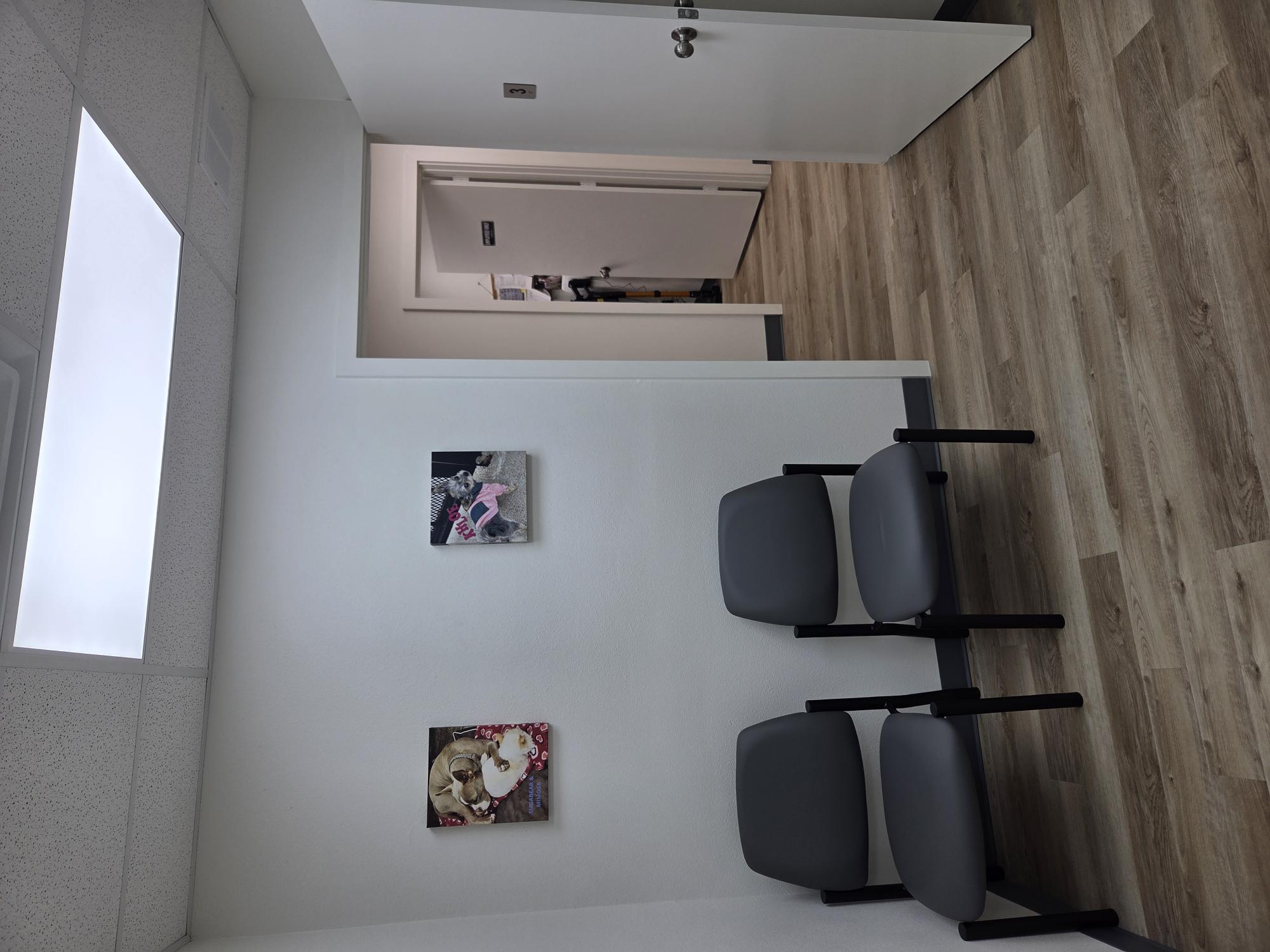 A room with two chairs and two paintings on the wall
