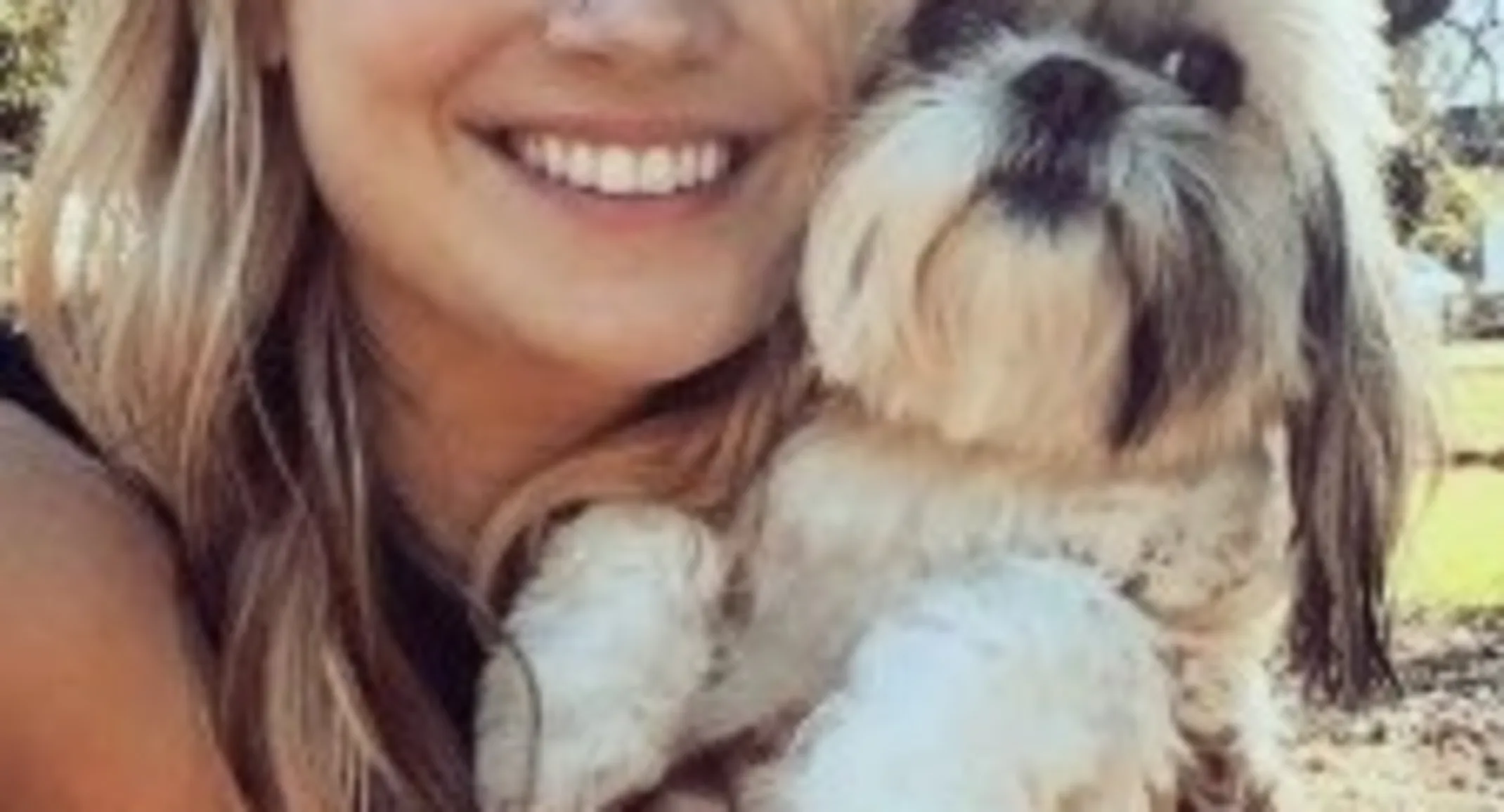a woman smiles while holding a small dog a woman smiles while holding a small dog
