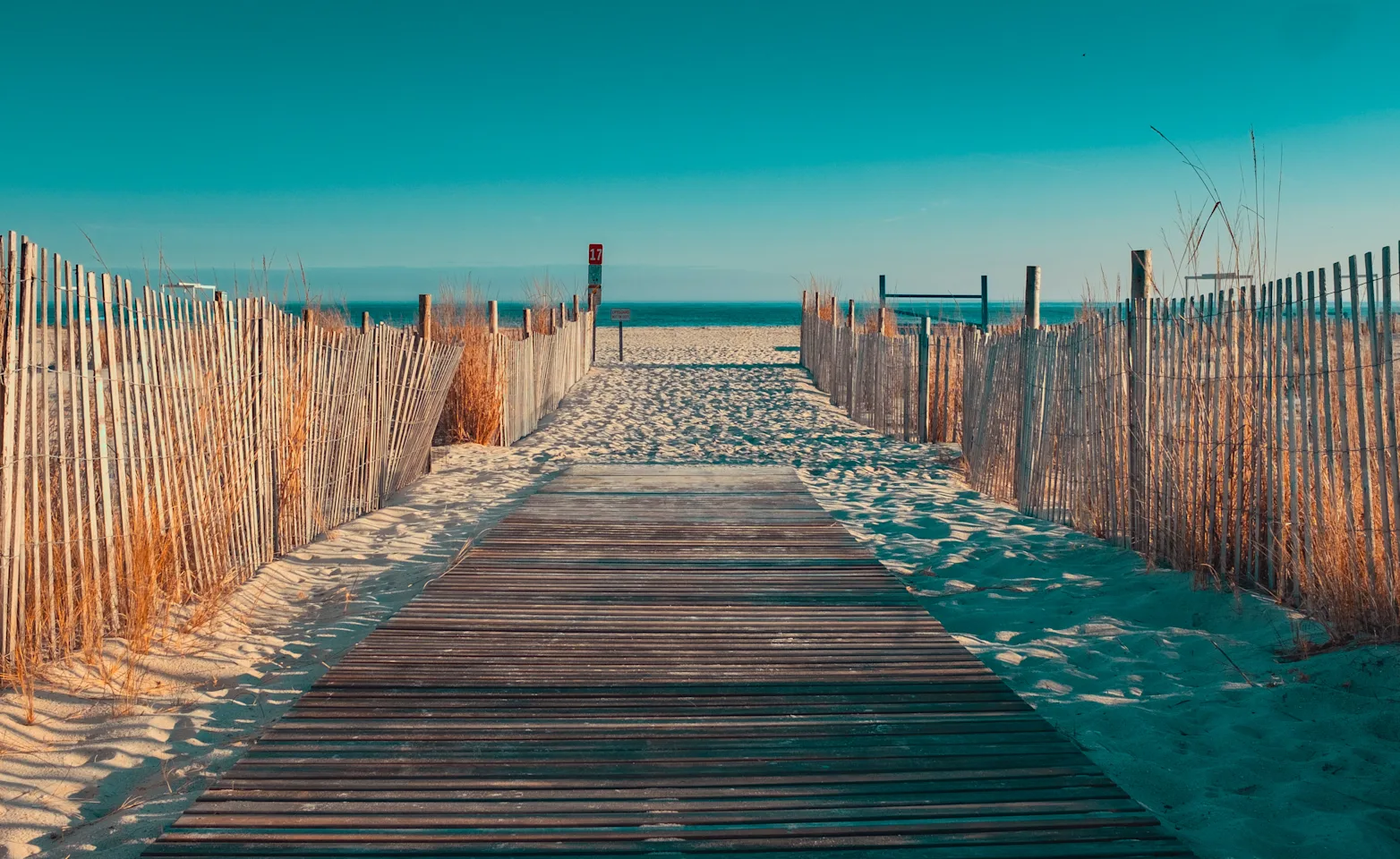 A pathway of made of wooden supports with a beachy view on the horizon A pathway of made of wooden supports with a beachy view on the horizon