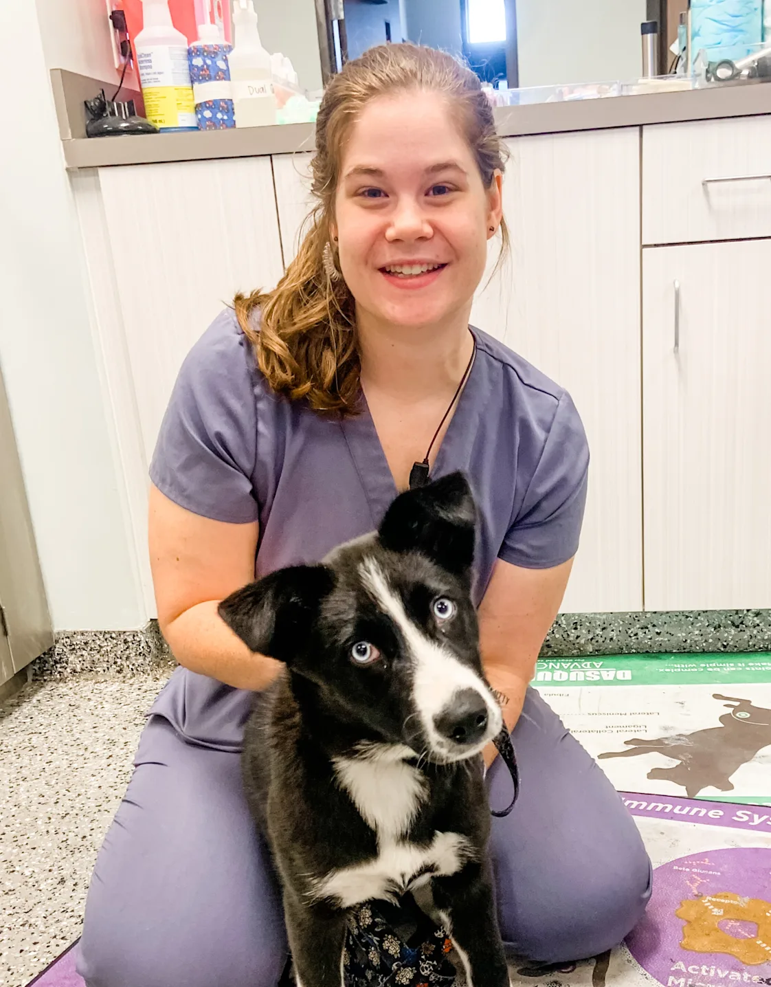 Alice Parker smiling kneeling down next to a black and white dog Alice Parker smiling kneeling down next to a black and white dog