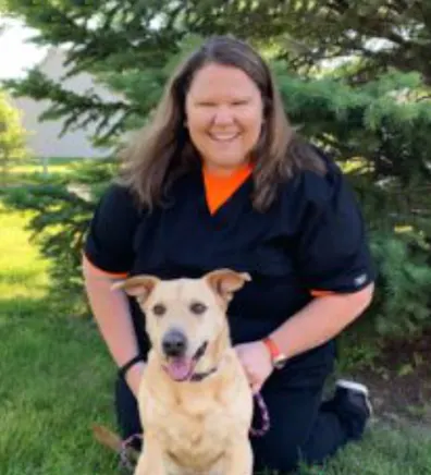 A staff member posing with a brown dog A staff member posing with a brown dog