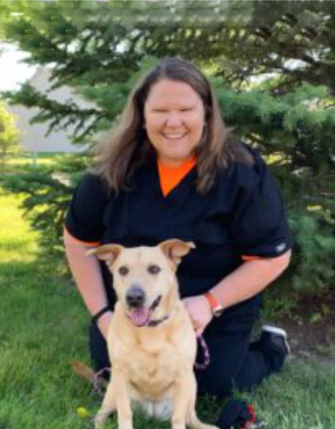 A staff member posing with a brown dog A staff member posing with a brown dog