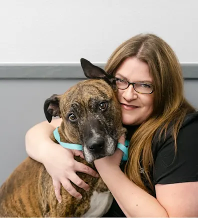 Sarah wearing a mask and holding a dog at All Pet Complex Veterinary Hospital