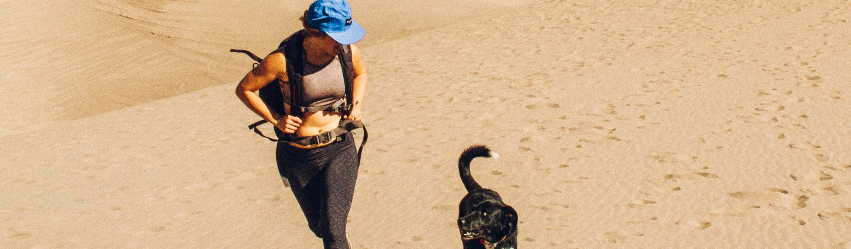 Dog and woman hiking in the sand