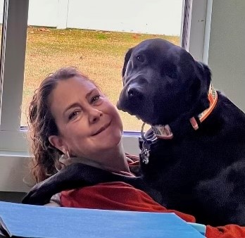 Staff member holding a black dog