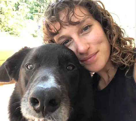 Hilary Strongs smiling next to a black lab. Hilary Strongs smiling next to a black lab.