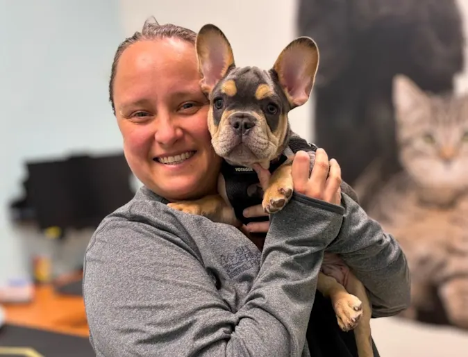 Alix smiling while holding a french bulldog. Alix smiling while holding a french bulldog.