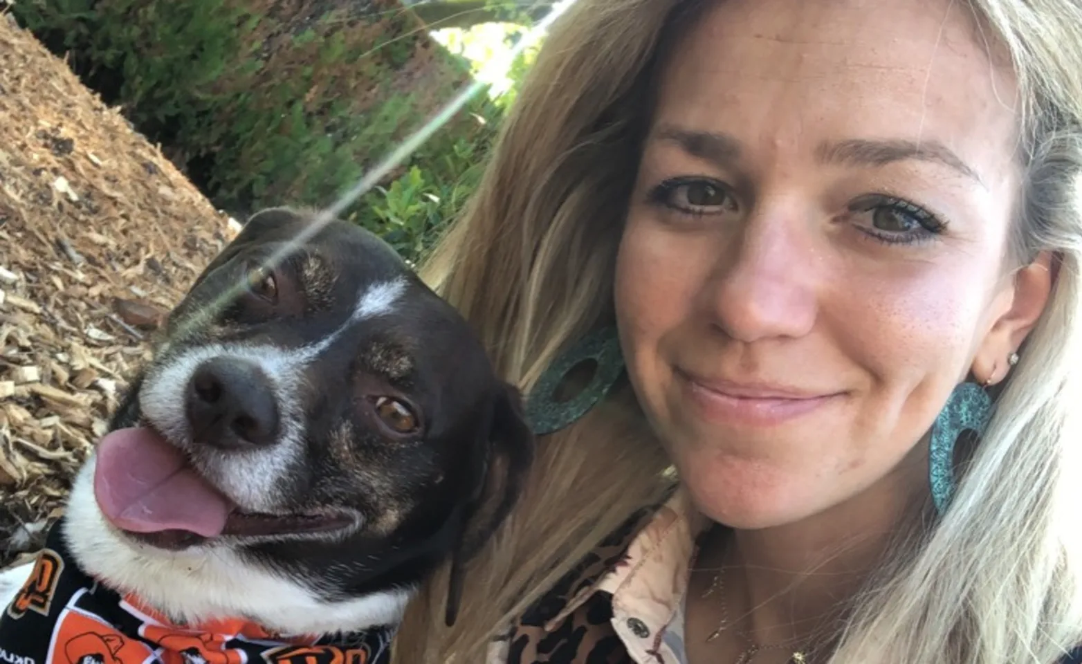 Dr. Kara Duh smiling with a friendly dog wearing a OSU bandana.