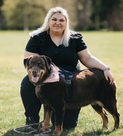 Sam Engh kneeling with a large brown dog 