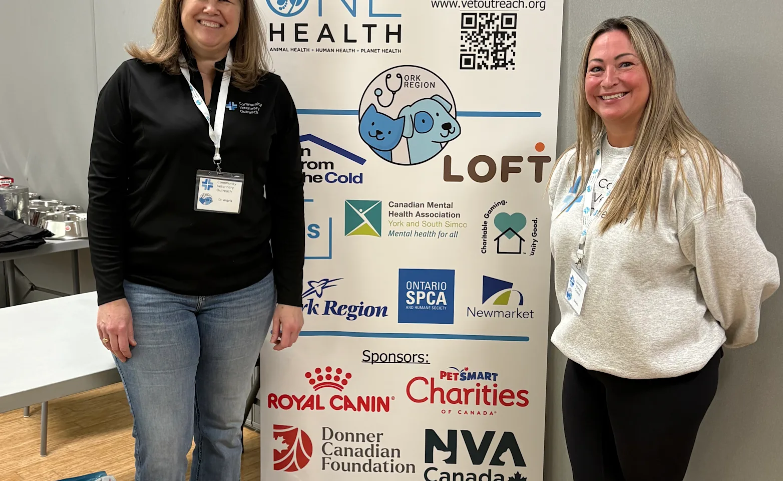 Two team members in front of the community veterinary outreach banner Two team members in front of the community veterinary outreach banner