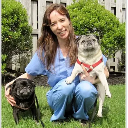 Jessica with 2 pugs in the grass.