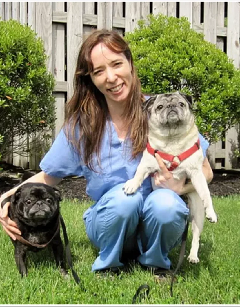 Jessica with 2 pugs in the grass.