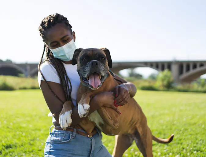 Girl wearing a mask and holding a dog