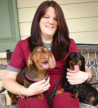 Meagan Tinch holding a brown dachshund and a black dachshund Meagan Tinch holding a brown dachshund and a black dachshund