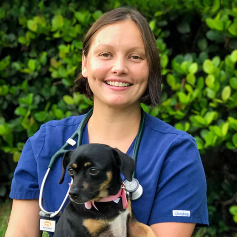 Dr. Cristiana Portus sitting down and holding a black puppy Dr. Cristiana Portus sitting down and holding a black puppy