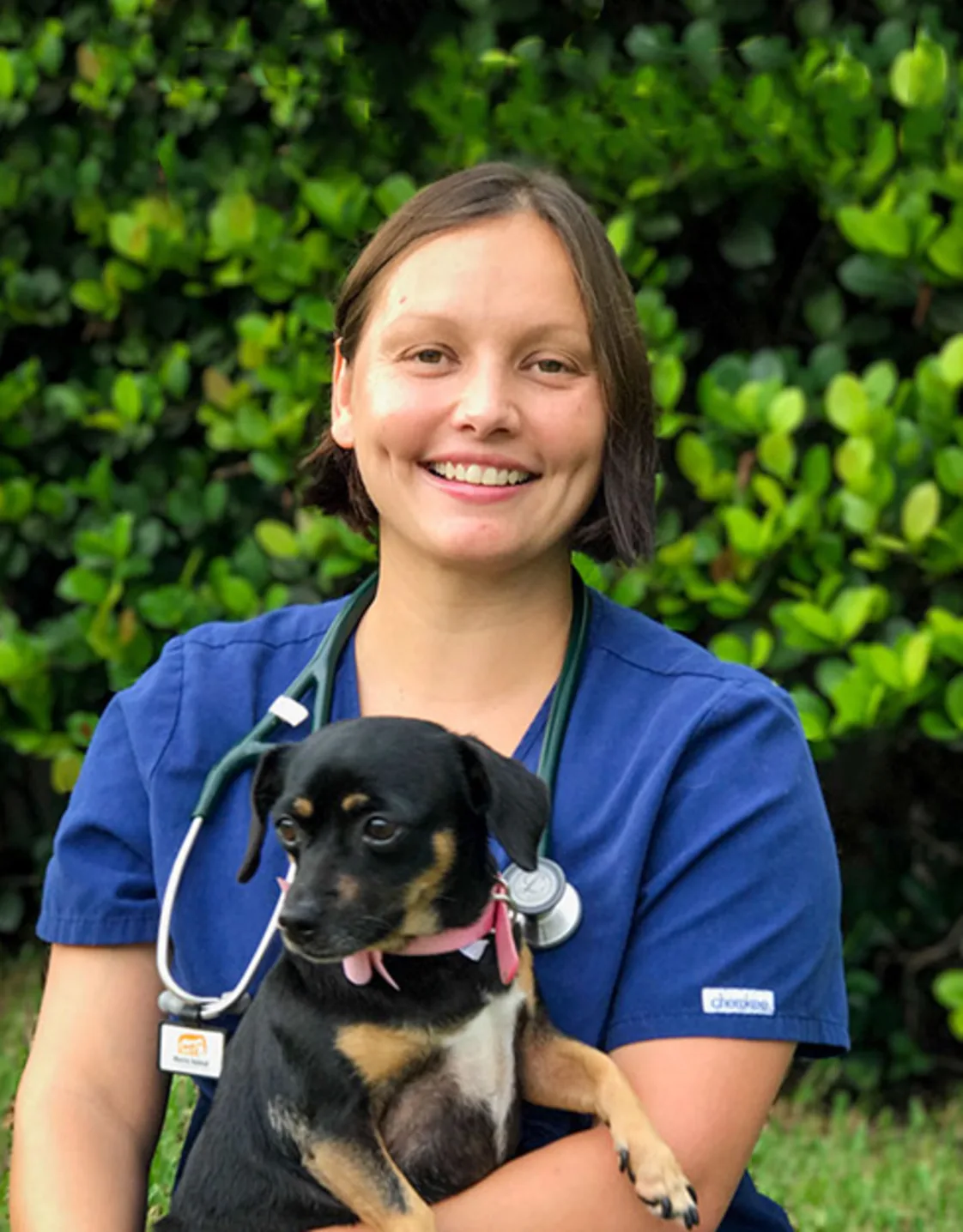 Dr. Cristiana Portus sitting down and holding a black puppy Dr. Cristiana Portus sitting down and holding a black puppy