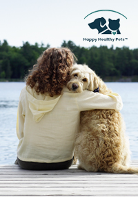 A woman with her arm around a dog sitting on a dock facing the lake.