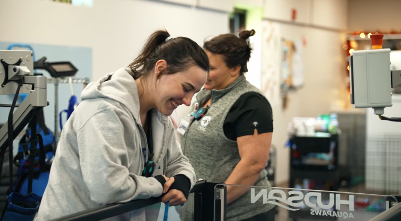Woman smiling while looking down at a underwater treadmill.