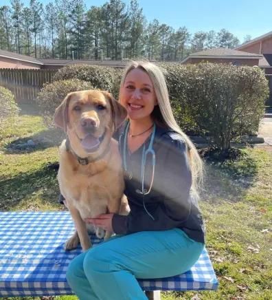 Morgan Bischoff sitting on an outside table with a dog.