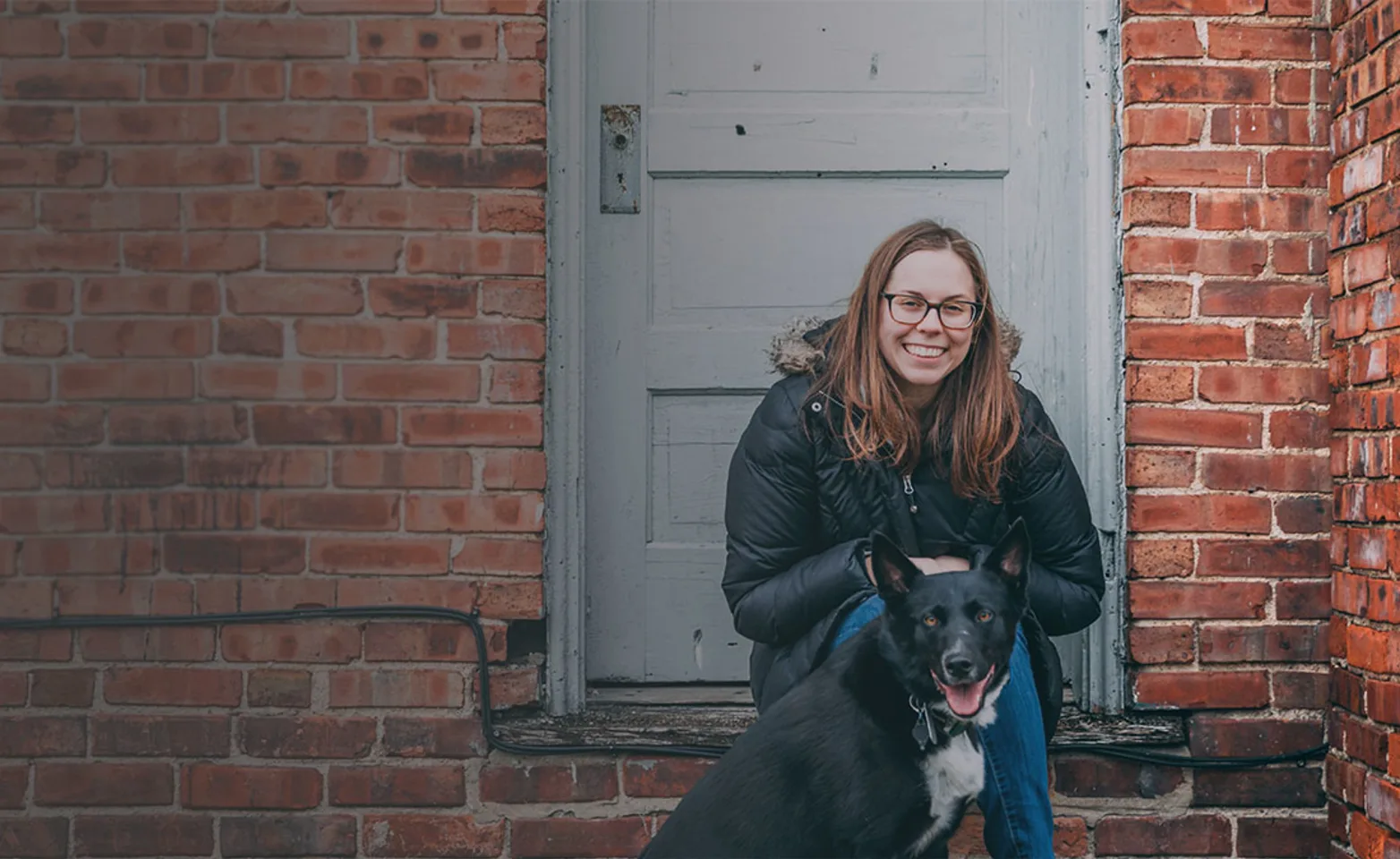Dog and woman sit in front of a door