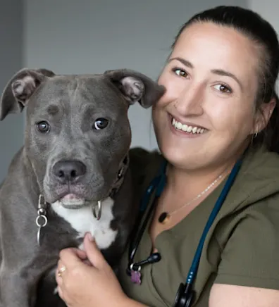 Chelsey smiling with a gray and white Pitbull