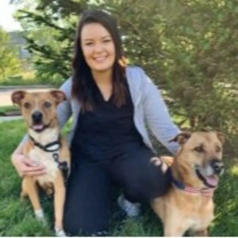 A staff member posing with two brown dogs A staff member posing with two brown dogs