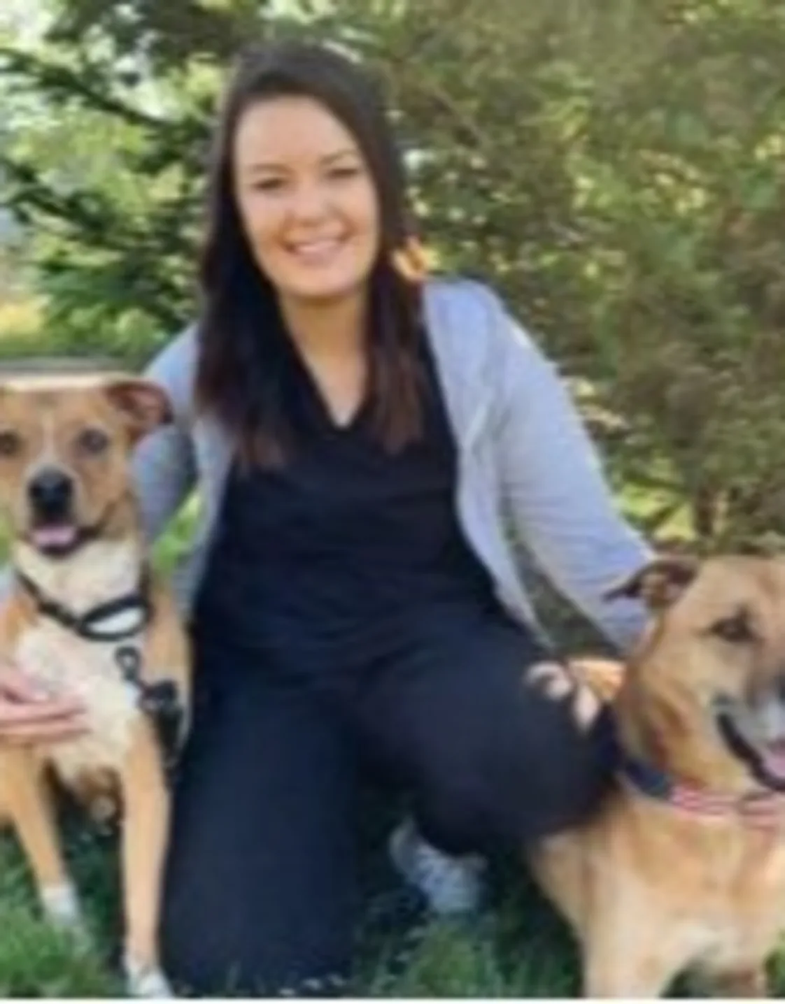 A staff member posing with two brown dogs A staff member posing with two brown dogs