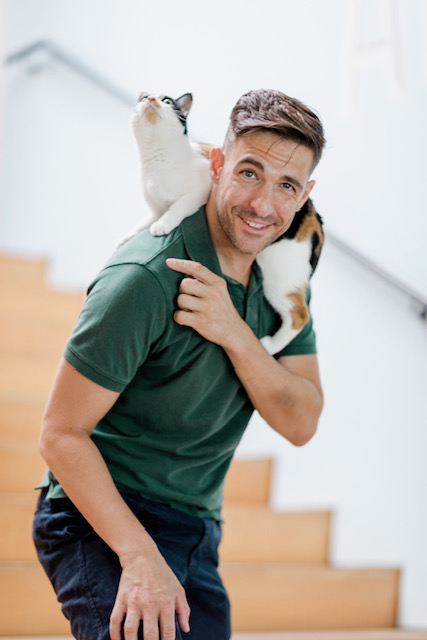 Jack Meagher in front of stairs carrying a cat.