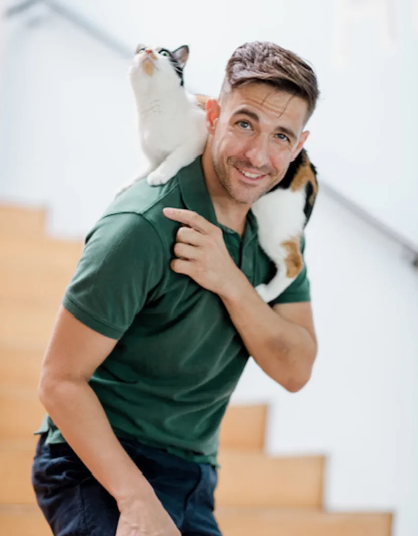 Jack Meagher in front of stairs carrying a cat.