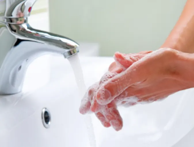 Washing hands in the sink to prevent the corona virus from spreading.