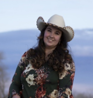 Dr. Wyman's staff photo where she is riding a horse in a desert with her cowgirl hat on.