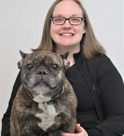 Angie of New Haven Pet Hospital posing with a brindle dog