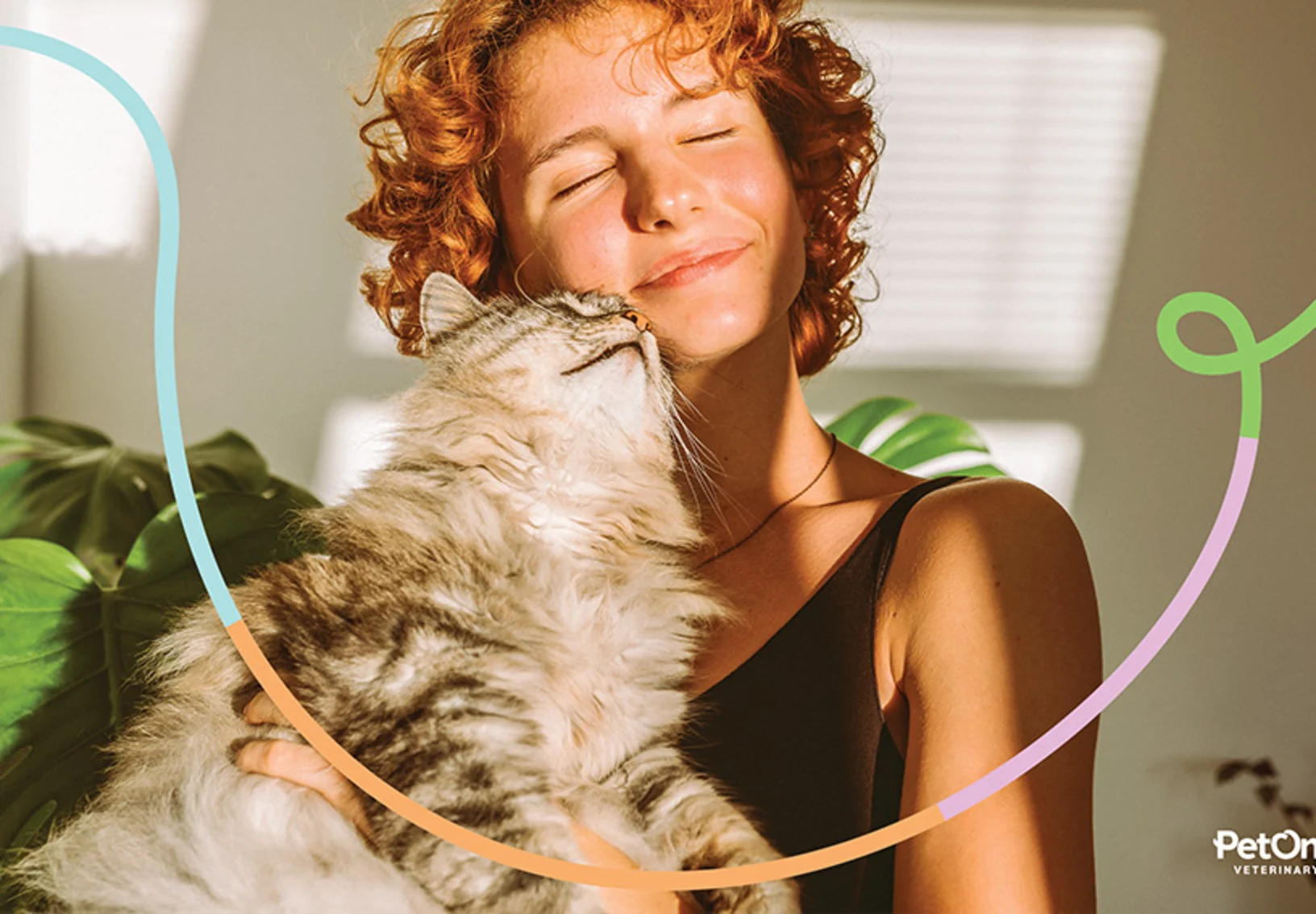 A woman smiling and holding her cat to her face in the sunlight of her window. A woman smiling and holding her cat to her face in the sunlight of her window.